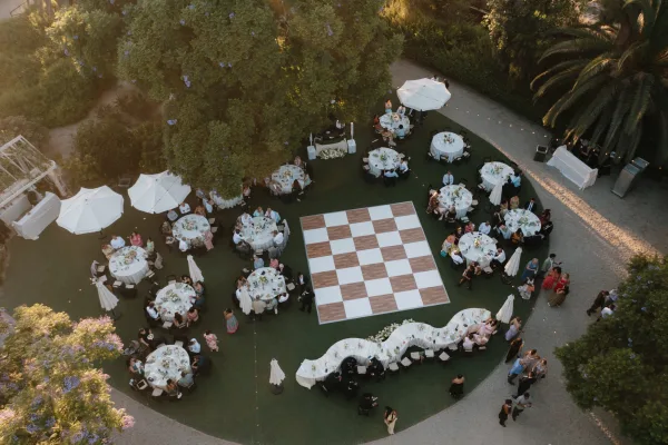 Outdoor reception setup highlighting a wedding reception layout featuring a dance floor on a palm-lined lawn
