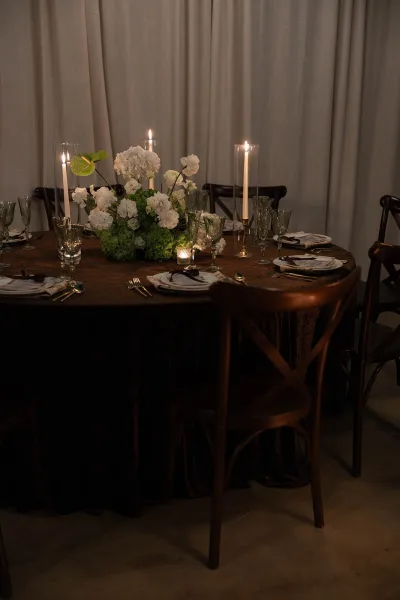 Reception tablescape styled as a candlelit wedding table, featuring green glass goblets at each place.