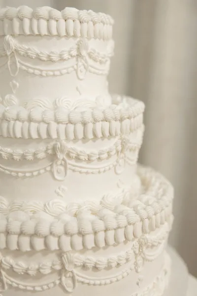 Buttercream wedding cake, a white wedding cake with round tiers and delicate scalloped borders, showcasing a timeless white-on-white look.