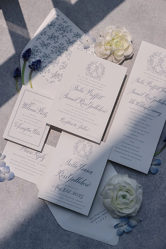 Wedding invitation suite with blue and white wedding invitations, monogram crest and floral liner, styled with ranunculus on linen shadows