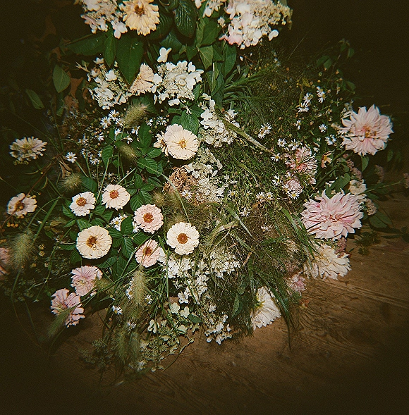 Bridal bouquet with wildflower bridal bouquet style, blush and white blooms with greenery in a flat lay on a wood floor