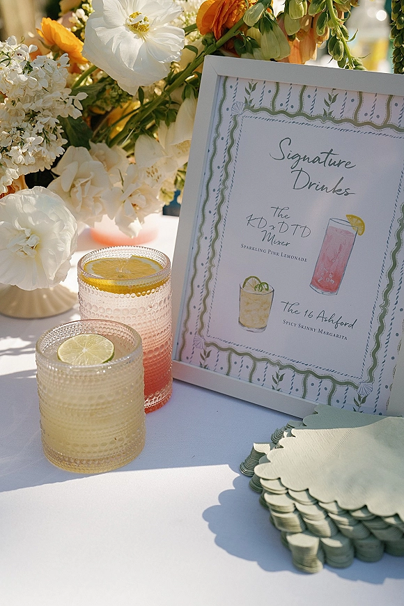 Signature drink sign with wedding signature drinks in a frame, cocktail illustration, textured tumblers with citrus slices on a sunlit tabletop