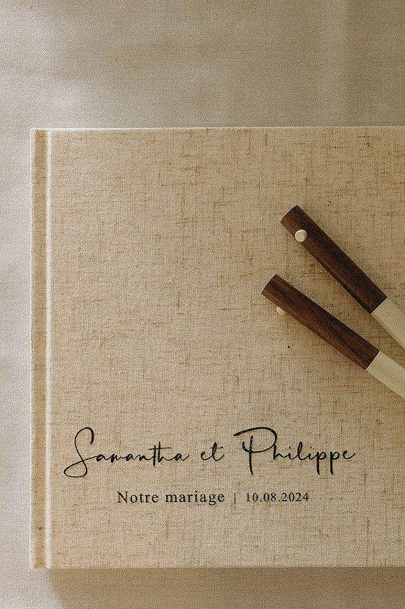 Wedding guest book with linen cover, calligraphy names and wedding date, styled with wood pen set on a neutral fabric surface