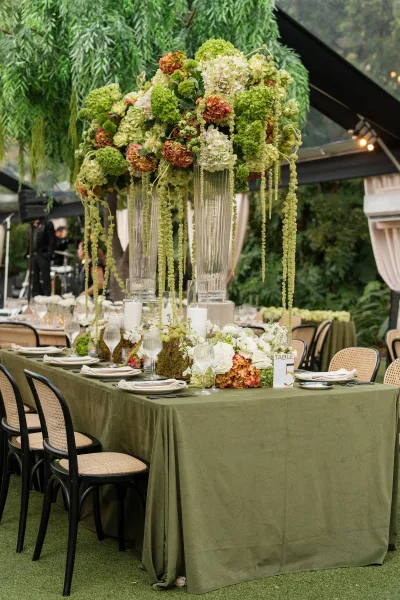 Reception tablescape styled for garden reception decor, featuring lush floral centerpieces beneath a clear tent with hanging foliage.