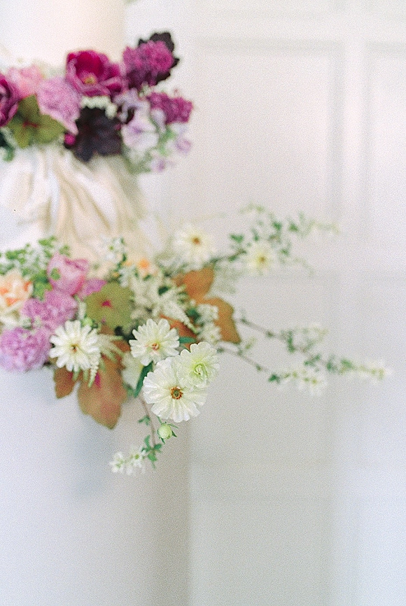 Wedding bouquet with purple and white bouquet blooms and greenery, ribbon-wrapped stems against a clean white fabric backdrop