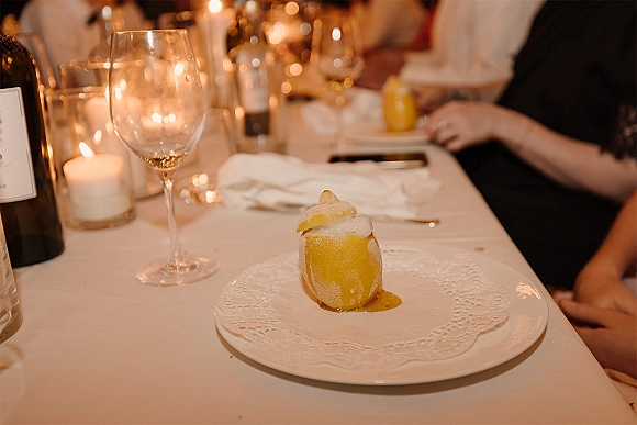 Wedding dessert plated wedding dessert on a white dinner plate beside a wine glass and candlelit glass votives at a warm reception table