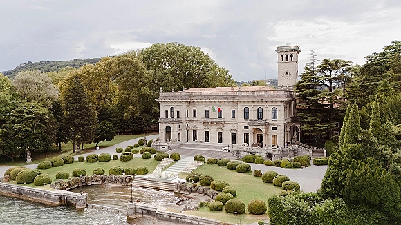 Outdoor wedding venue with villa wedding venue ceremony chairs and a white aisle runner on a terrace overlooking a lake and hills under clouds