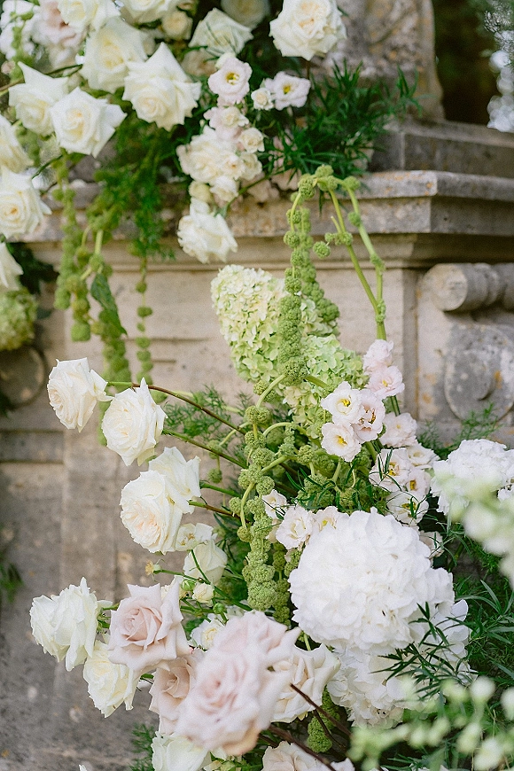 Wedding floral arrangement with white rose wedding flowers cascading with hydrangea and greenery along stone steps and balustrade