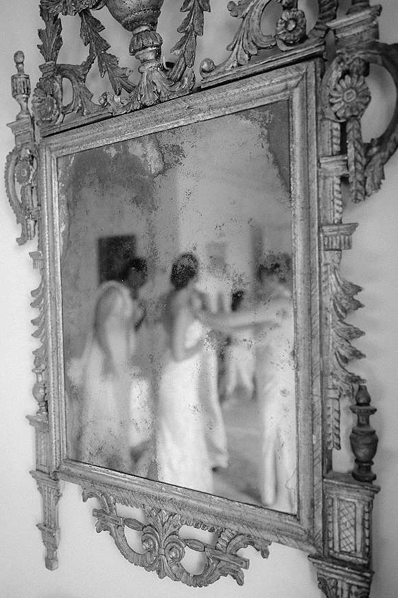 Wedding mirror photo showing bride reflection photo in an antique ornate frame, capturing a candid getting-ready moment in a bridal suite room