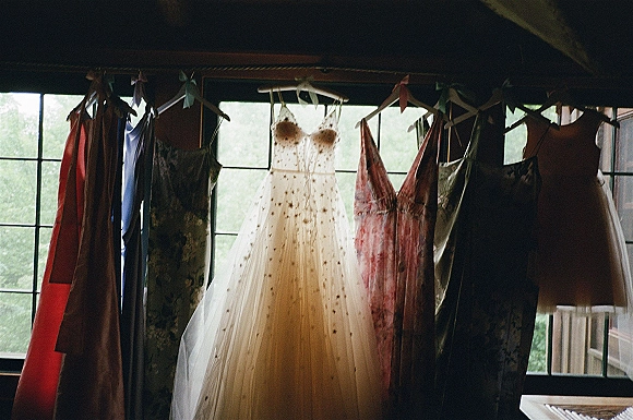 Wedding dress bridal gown on hanger with spaghetti straps and embroidered bodice, tulle skirt glowing by a large window with beams