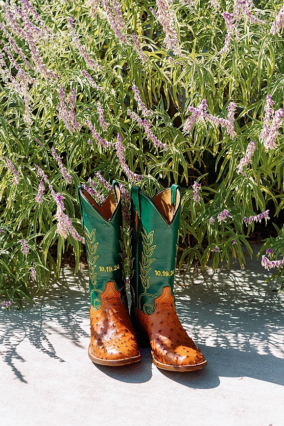Wedding boots with cowboy boots styling, leather and embroidered stitching with stamped wedding date beside lavender flowers in sunlight
