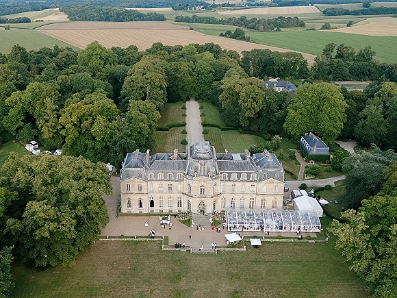 Wedding venue aerial showing an estate wedding venue mansion with clear top tent and outdoor tables on manicured lawn, gardens and fields