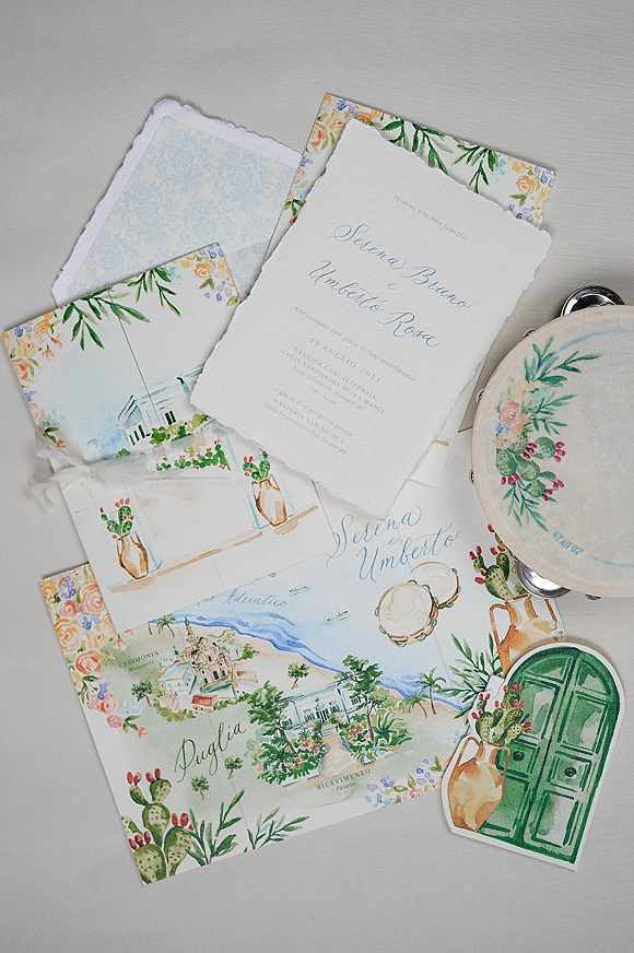 Invitation suite with deckle edge wedding invitation in blue calligraphy, floral envelope liner, RSVP, details and map cards on neutral tabletop