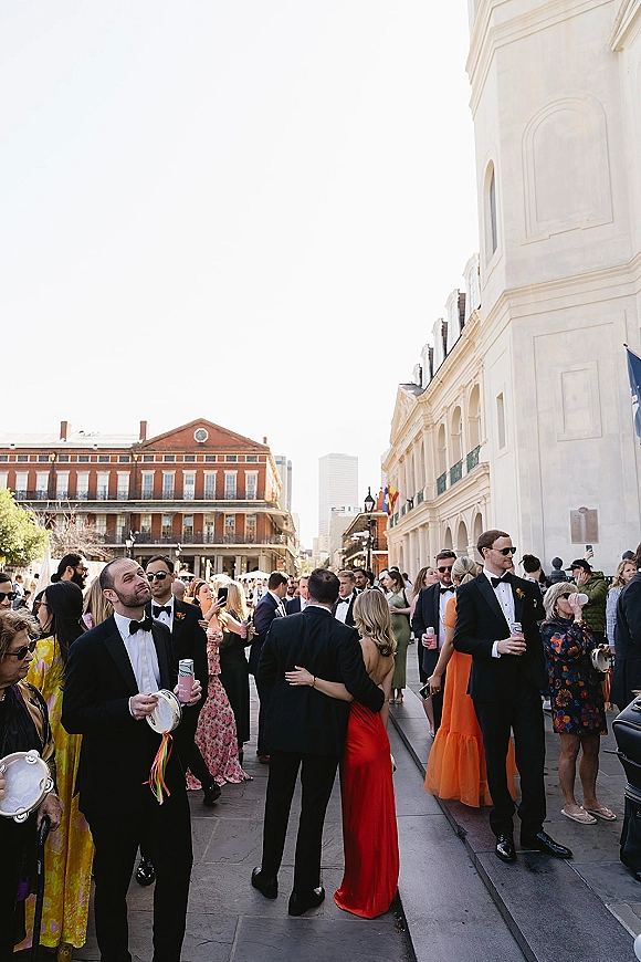 Wedding exit wedding second line as guests in tuxedos and evening gowns parade down a city street with tambourines and ribbon streamers