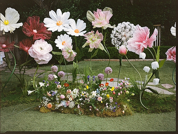 Floral ceremony installation with giant paper flowers wedding decor, a meadow-style arrangement on faux grass carpet on a garden lawn with hedges