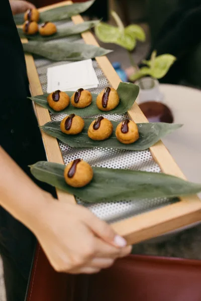 Wedding appetizers served as passed hors d'oeuvres on a wooden serving tray during cocktail hour service.