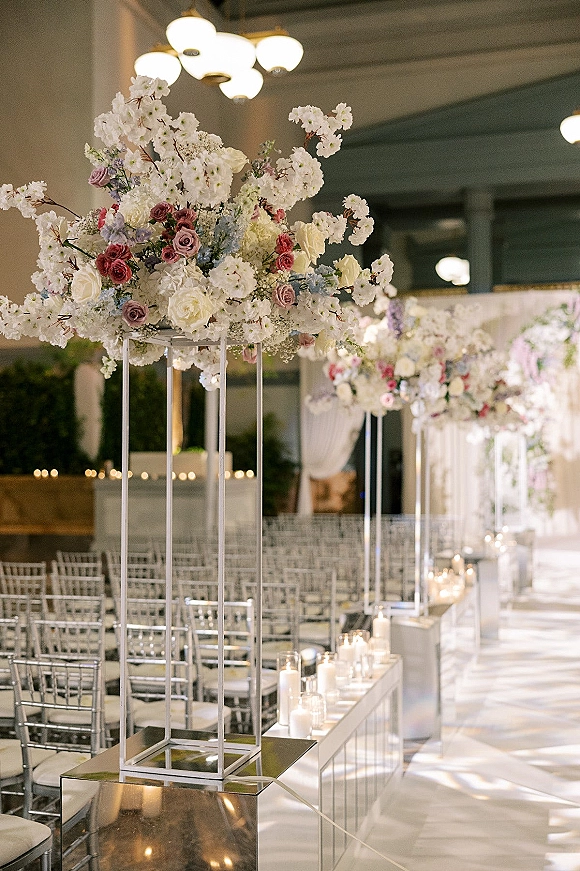 Ceremony aisle decor with candlelit wedding aisle, tall rose and cherry blossom arrangements on mirrored pedestals in a ballroom