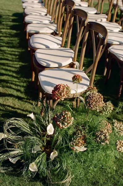 Ceremony aisle decor framing outdoor ceremony seating with low floral clusters of calla lilies lining the chair ends.