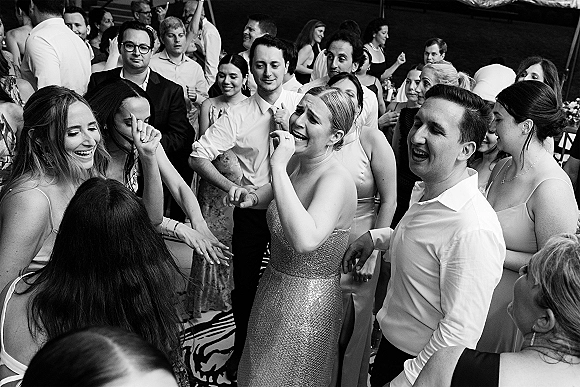 Wedding dance floor packed with wedding reception dancing, bridesmaids in mixed dresses and guests moving together in an indoor reception space