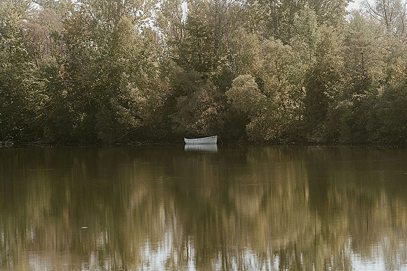 Rowboat on lake, a white rowboat resting on calm water with still reflections and a forested shoreline in the background