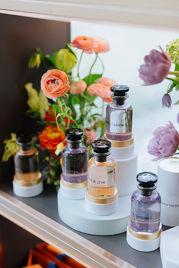 Wedding perfume details in a bridal perfume flat lay with perfume bottles and ranunculus blooms on a tray in soft window light