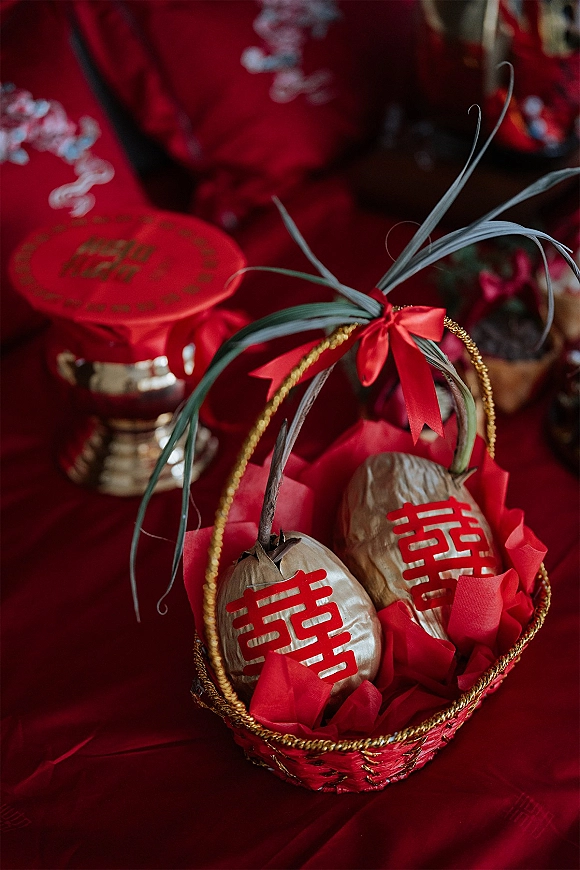 Wedding gift basket, Chinese wedding gift basket with red ribbon bow, gold trim and palm leaves against red embroidered textiles backdrop