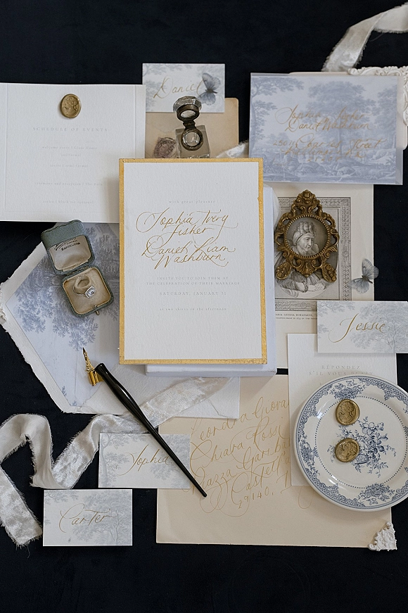 Invitation suite wedding invitation flat lay with calligraphy cards, wax seals, silk ribbon, ring box and engagement ring on dark tabletop