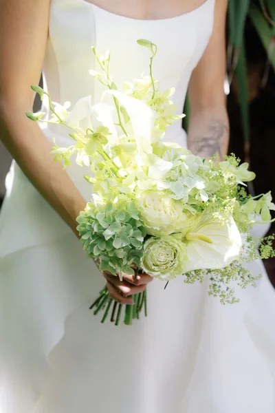 Bridal bouquet, a green and white bouquet with hydrangea clusters, softly rounded and lush, set against garden foliage.