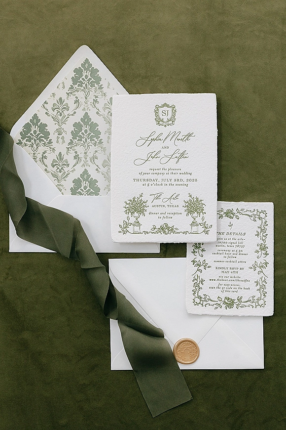 Wedding invitation suite with letterpress wedding invitations, ribbon and wax seal, arranged with envelope liner on green fabric backdrop