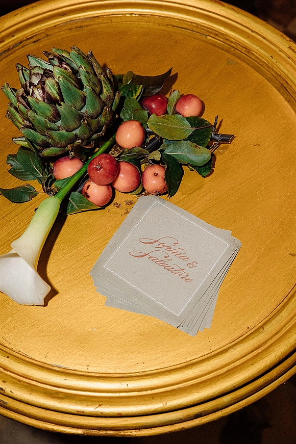 Wedding place cards with calligraphy place cards on a gold round tray, deckle edge paper paired with a calla lily and greenery on tabletop