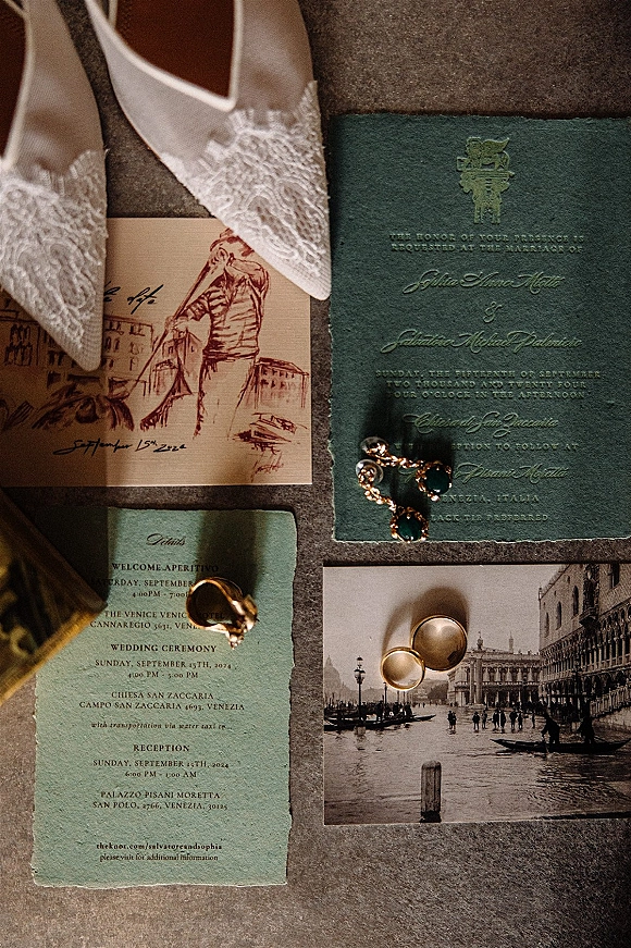 Invitation suite wedding invitation flat lay with embossed card, lace bridal shoes, rings and gold jewelry arranged on a stone surface