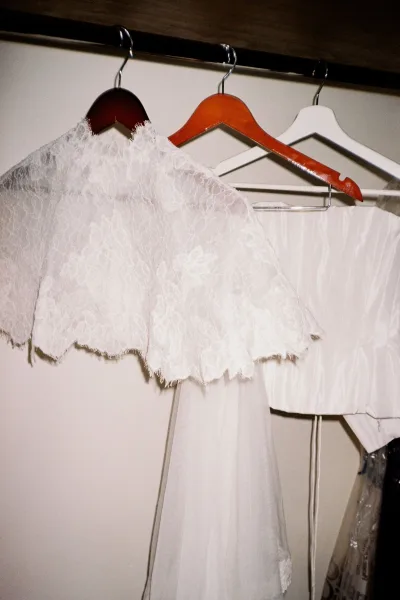 Wedding dress close-up featuring a lace bridal cape layered over sleek fabrics, capturing delicate textures and refined minimalist bridal style.