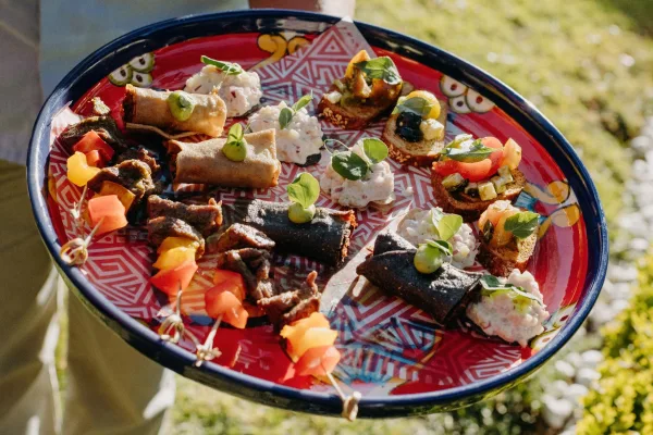 Wedding appetizers served as passed hors d'oeuvres, featuring crostini, with a sunlit garden lawn and greenery behind.