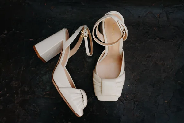 Bridal shoes, ivory block heel sandals with a delicate ankle strap, styled in a clean, modern silhouette for an elegant wedding day look.