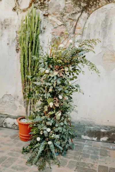 Ceremony floral installation as an altar floral arrangement, sculptural and organic, anchored by a potted cactus.