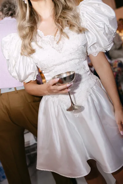 Short wedding dress styled as a puff sleeve wedding dress, captured at a warmly lit indoor reception setting.