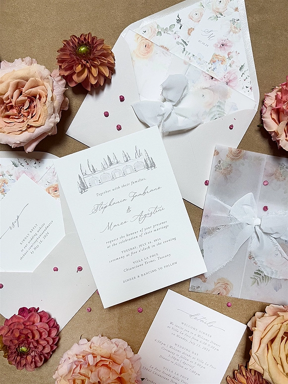 Wedding invitation suite with floral wedding invitations tied in white ribbon, lace and wax seal, styled with blooms on kraft paper surface