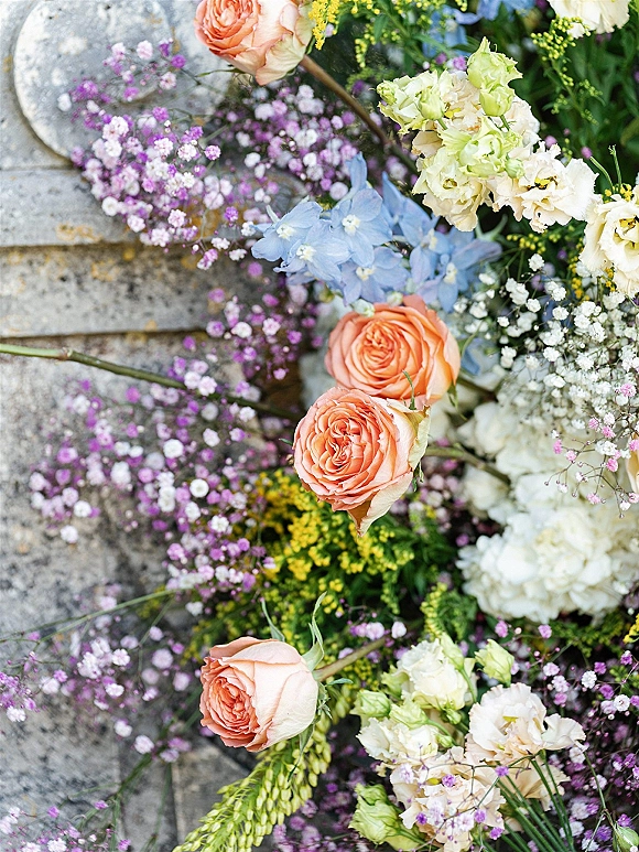 Wedding flowers featuring peach rose wedding flowers with baby’s breath accents arranged in a loose pastel mix on stone steps