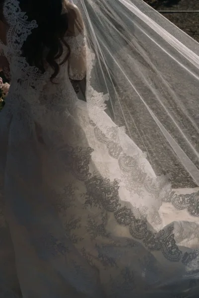 Lace wedding dress, an ivory lace gown with a long veil, flows elegantly as intricate lace catches the light.