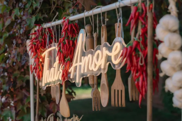 Wedding signage featuring a neon wedding sign framed by chili peppers against ivy-laced garden greenery