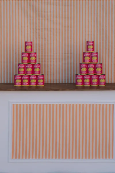 Reception backdrop as a striped wedding backdrop, stacked with canned tomatoes against white panel molding.