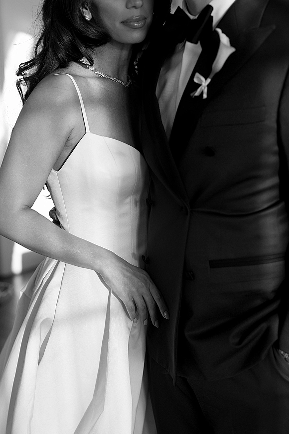 Couple portrait in a black and white wedding portrait, bride and groom close up embracing in tuxedo and strapless gown on blurred indoors background