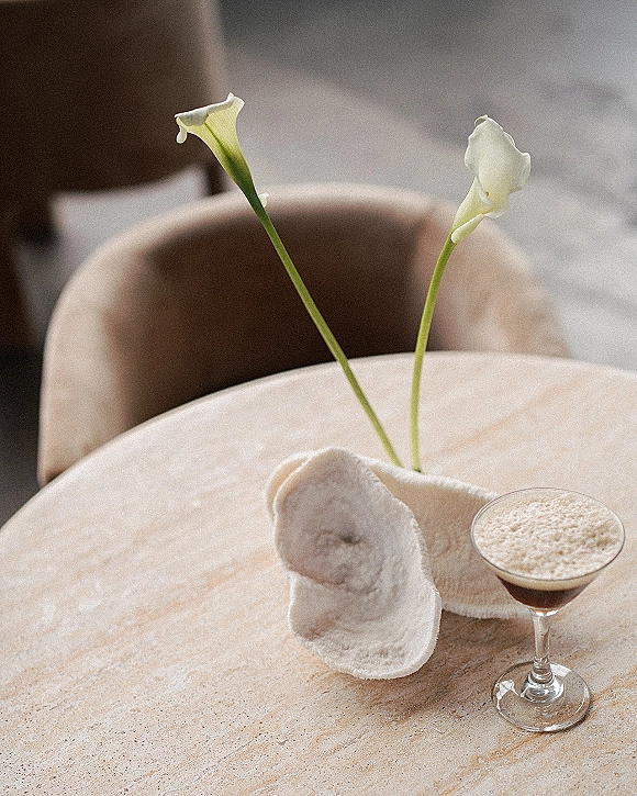 Reception tablescape with a minimal wedding tablescape calla lily in a ceramic vase, espresso martini in a coupe glass on a round stone table