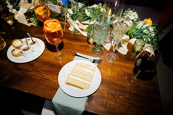 Reception tablescape with wood wedding table decor, floral garland, taper candles in glass holders, and vintage glassware on a wooden table