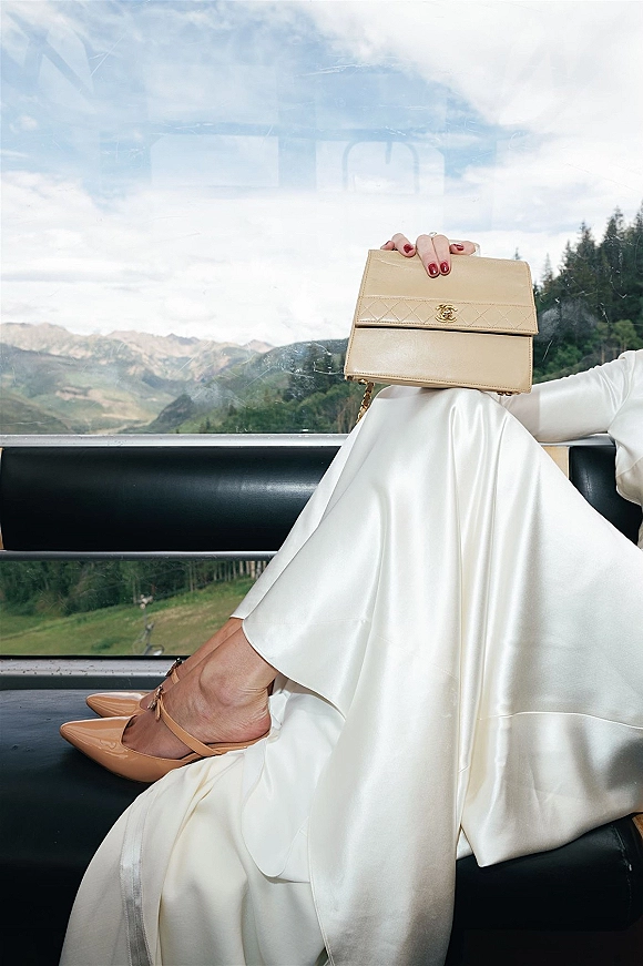 Bridal accessories with wedding clutch purse, nude ankle-strap heels and engagement ring with red nails in a gondola over mountains