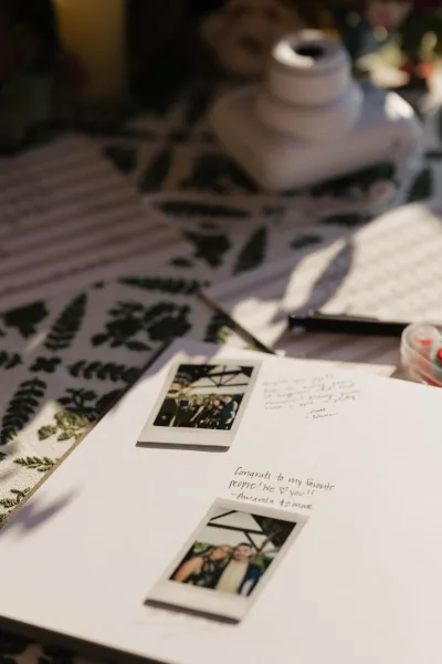 Wedding guestbook with polaroid wedding guestbook instant photos, handwritten notes, and photo corners on white pages at a tabletop station