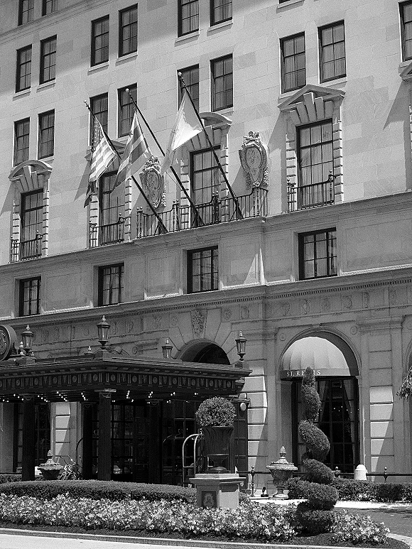 Wedding venue exterior with a hotel wedding venue canopy, flags, and lantern lights against a stone facade with balcony railings