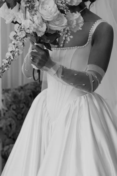 Bridal portrait of a bride holding bouquet, wearing pearl gloves that complement her classic gown with timeless poise.