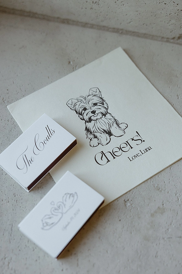 Wedding matchbooks and custom matchbook favors with calligraphy labels, illustrated dog artwork, and thank you card on a stone tabletop