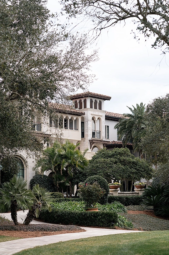 Wedding venue exterior with Mediterranean wedding venue charm, featuring an arched colonnade and palm trees along a manicured walkway